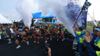 Rombongan pelari memulai start East Java Running Festival di Banyuwangi, diiringi confetti dan asap.