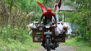 Suaidi, pedagang sayur dengan kostum Spiderman, sedang berjualan di Banyuwangi.
